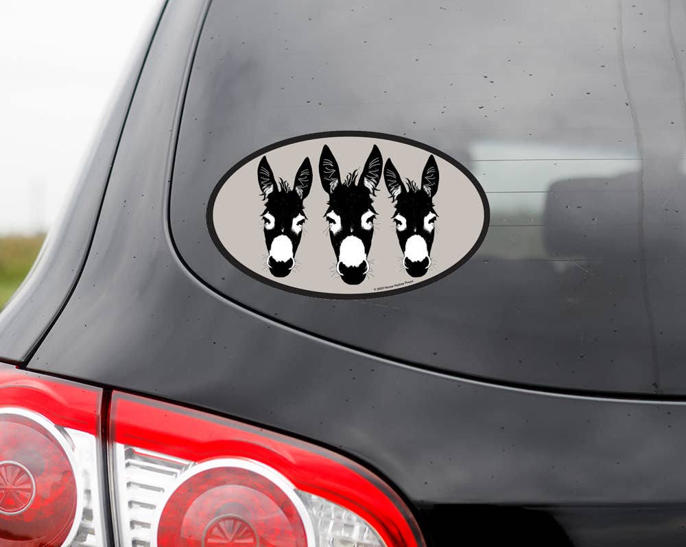 Car decal with three donkey faces on a vehicle's rear window.