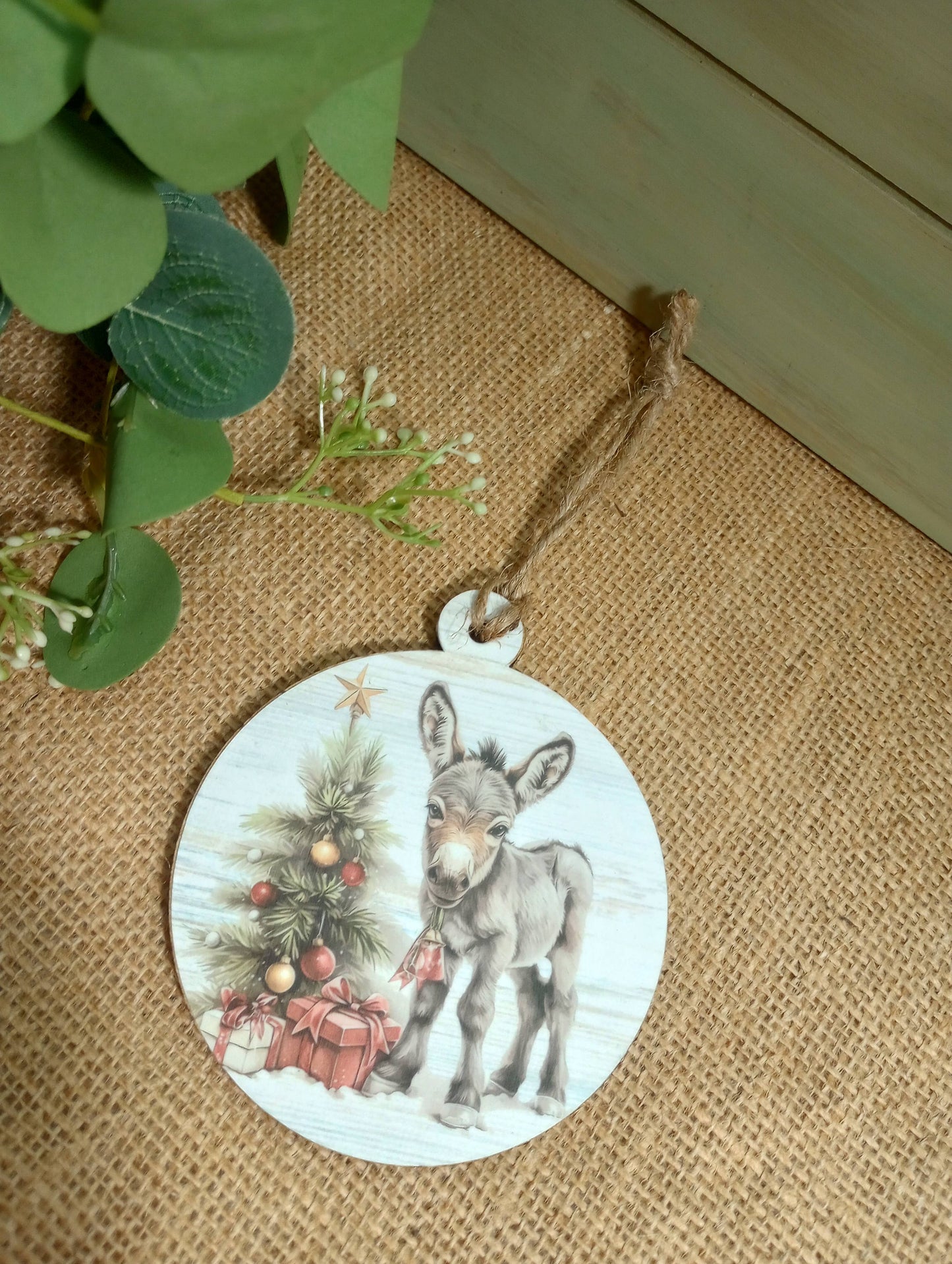 Round Christmas ornament with a donkey and tree design on a textured surface.
